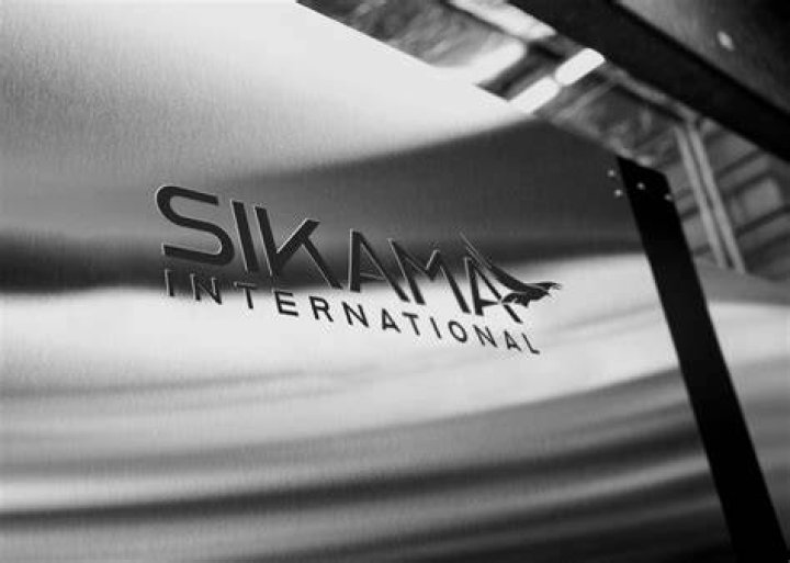 Interior of Sikama International, bright blue Falcon 5C machines in a row below a large Sikama International sign
