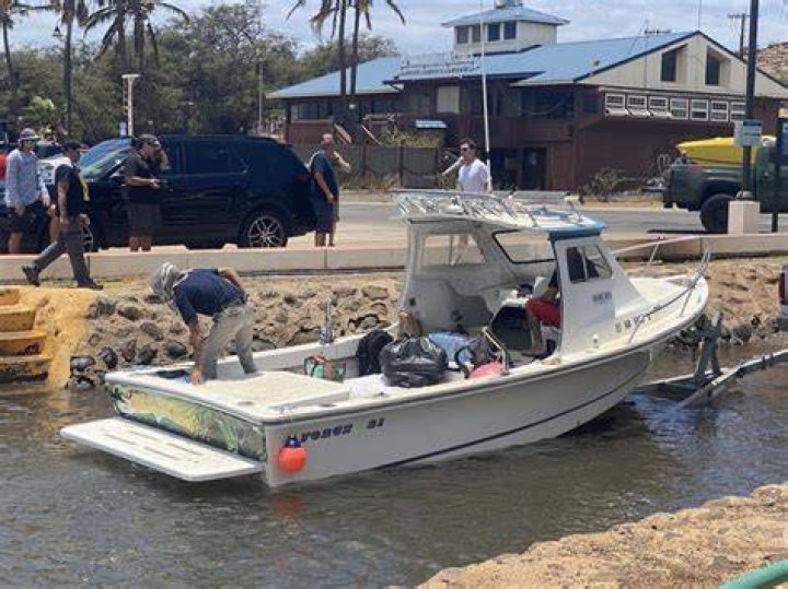Residents load up a boat as they evacuate from a beach as the flames roll in